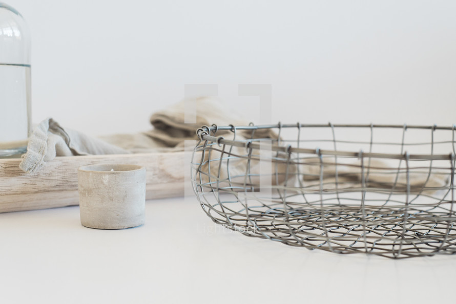 wire basket, votive candle, linen fabric, and vase of water 