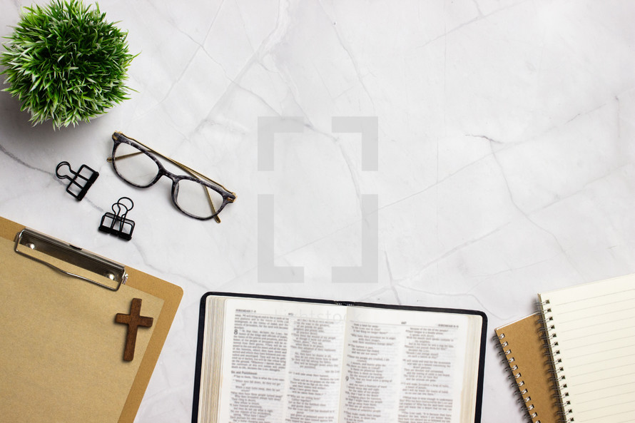 open Bible, notebook, and reading glasses on a desk 
