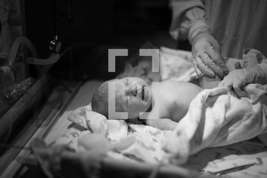 Nurse swaddling a newborn infant.
