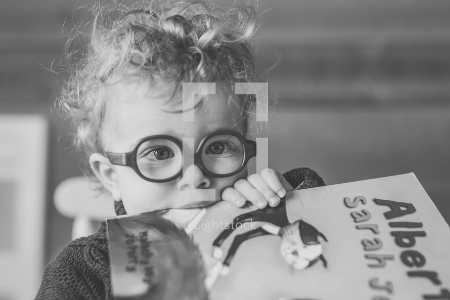 a child with glasses holding a book 