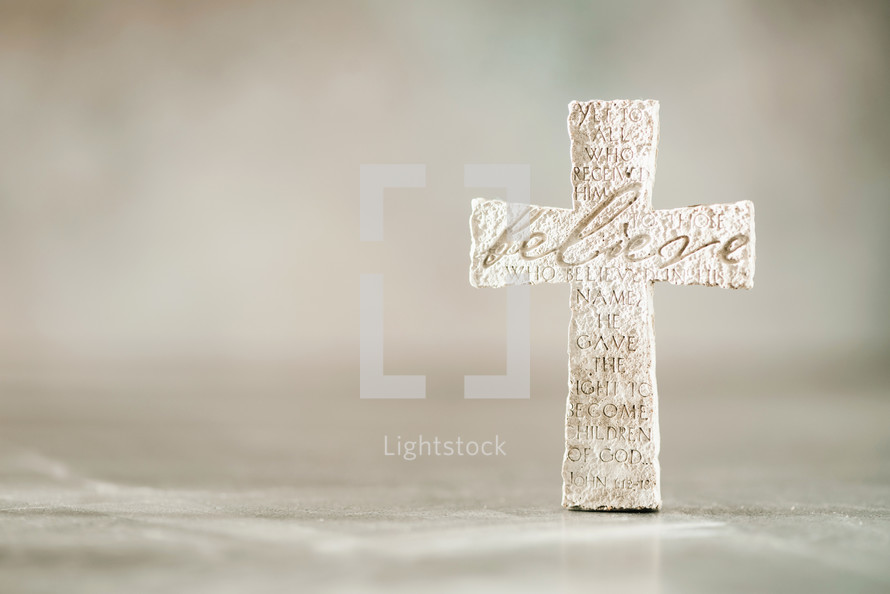 Stone cross with inscription Believe. 