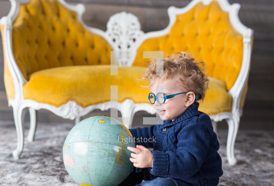 a child sitting on the floor playing with a globe 