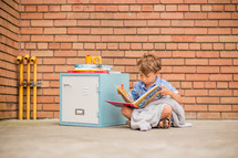 a boy reading a book next to a locker 