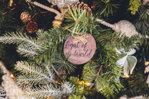 Wooden ornament with the word "Light of World" on a Christmas tree 