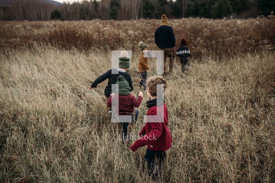 children running through a field of tall brown grass 
