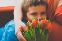 a boy giving his mother flowers for mother's day