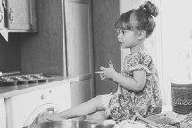 toddler girl sitting on a kitchen counter 