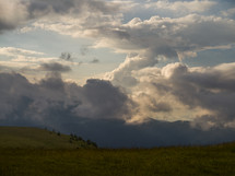 clouds over a green mountaintop 