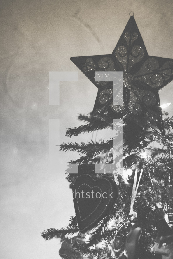 A star ornament at the top of a Christmas tree 