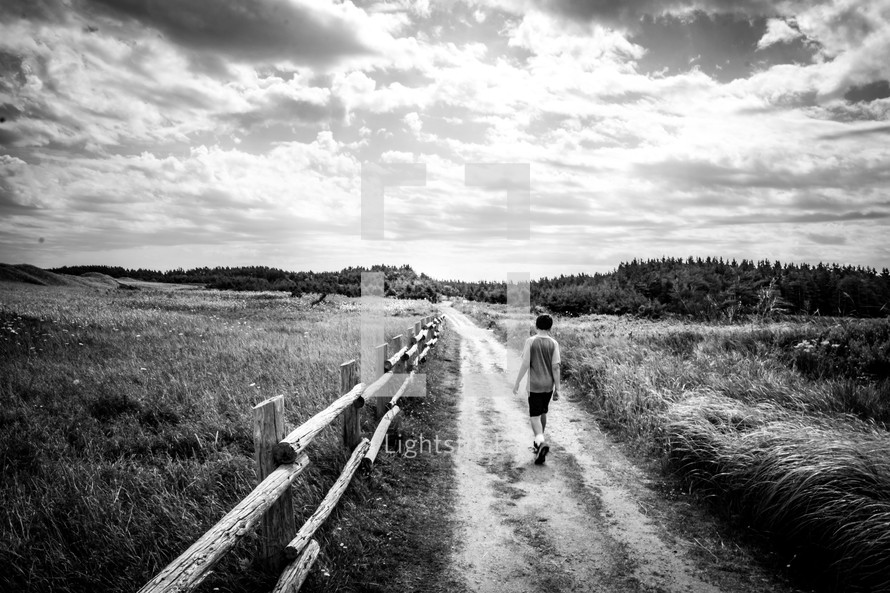 boy walking on a dirt road 