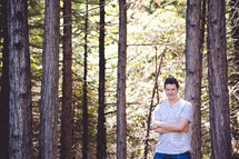man with crossed arms standing in a forest 