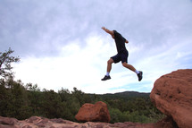 man jumping from a rock ledge