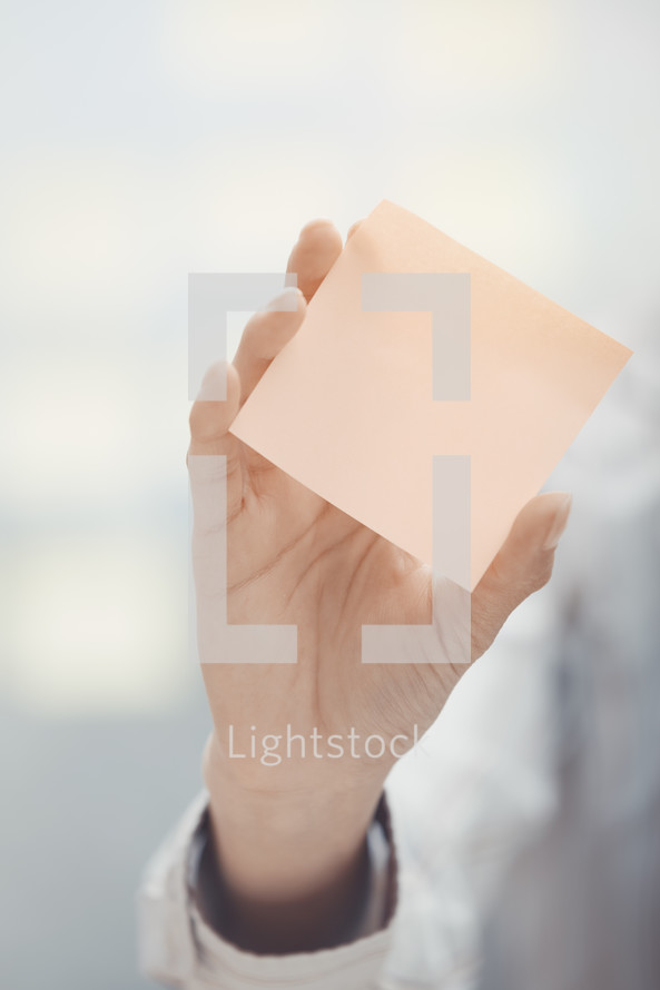 a person holding a blank sticky note 