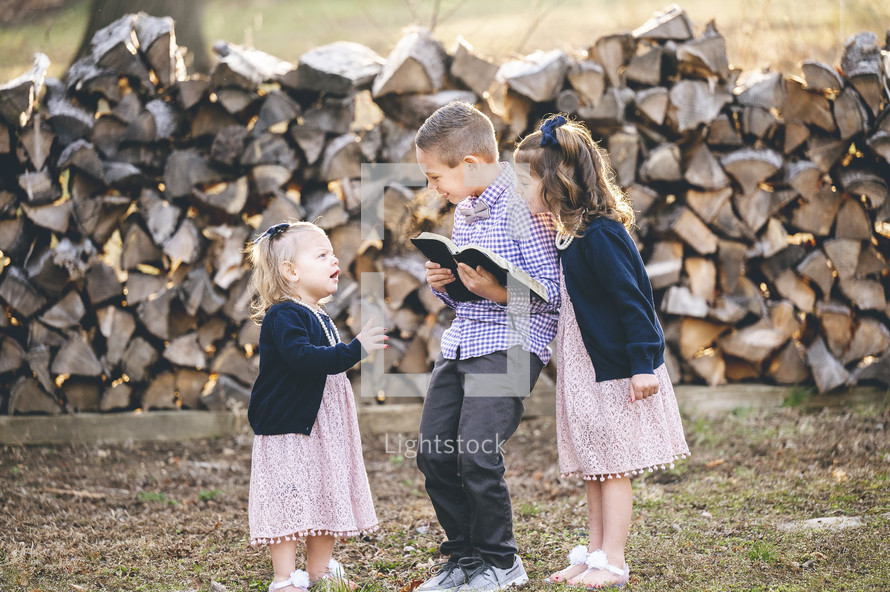 brother and sisters standing together holding a Bible on Sunday morning 
