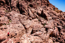a man exploring red rock cliffs 