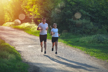 people jogging and exercising in nature, in morning sunrise warm light