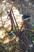 A bike resting against a tree. 