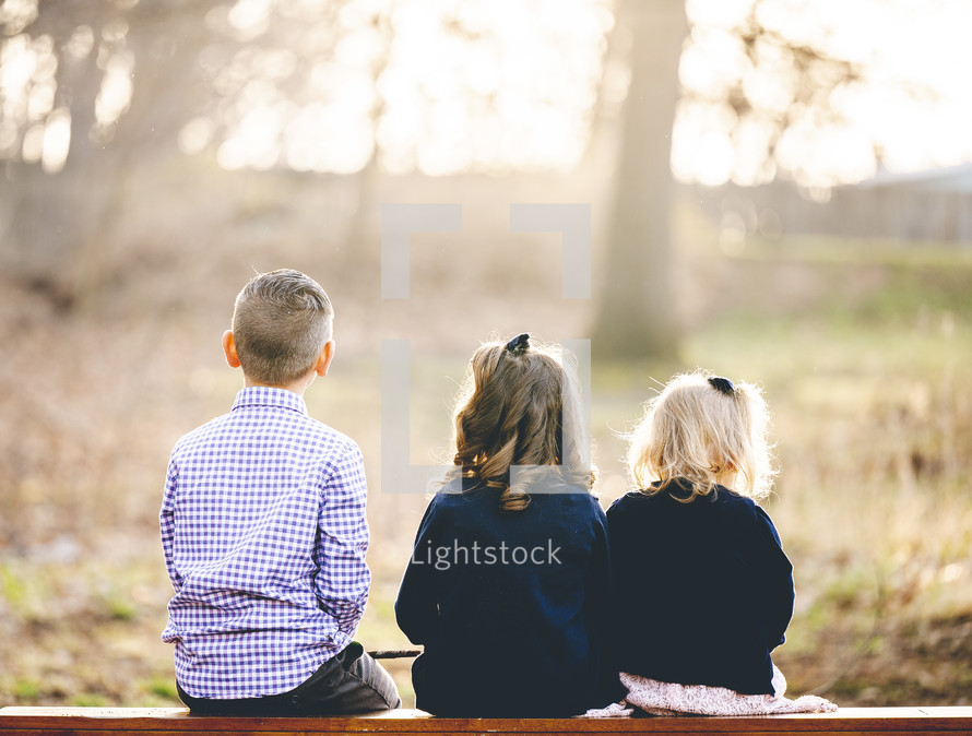 kids sitting on a bench with back to the camera 