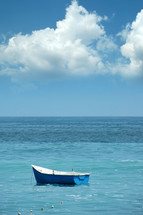 A small blue boat floating in a calm sea.