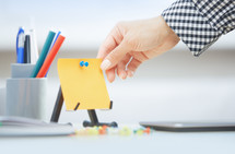 a woman reaching for a blank sticky note 