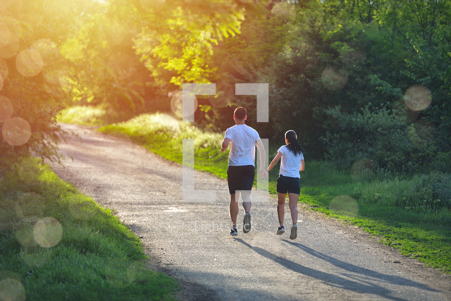 Young people jogging and exercising in nature, in morning sunrise warm light