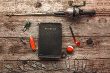 fishing pole and lures beside a Bible 