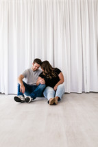 couple snuggling sitting on the floor of an empty house 