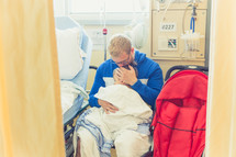 a father comforting his son in a hospital gown in a hospital 