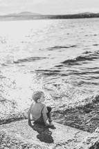 a child sitting on a shore 