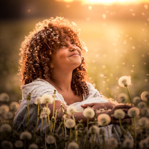 smiling girl looking up to God in a field of dandelions 