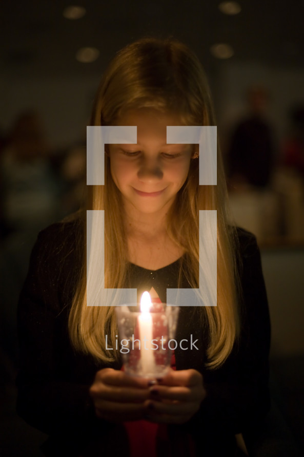 A child holding a candle at a Christmas eve worship service. 