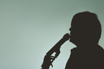silhouette of a man singing into a microphone 