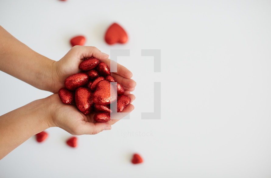 cupped hands holding red Valentines hearts 