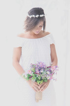 A bride holding a bouquet of flowers looking down in prayer 