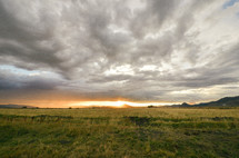 cloudy skies over a field at sunset 