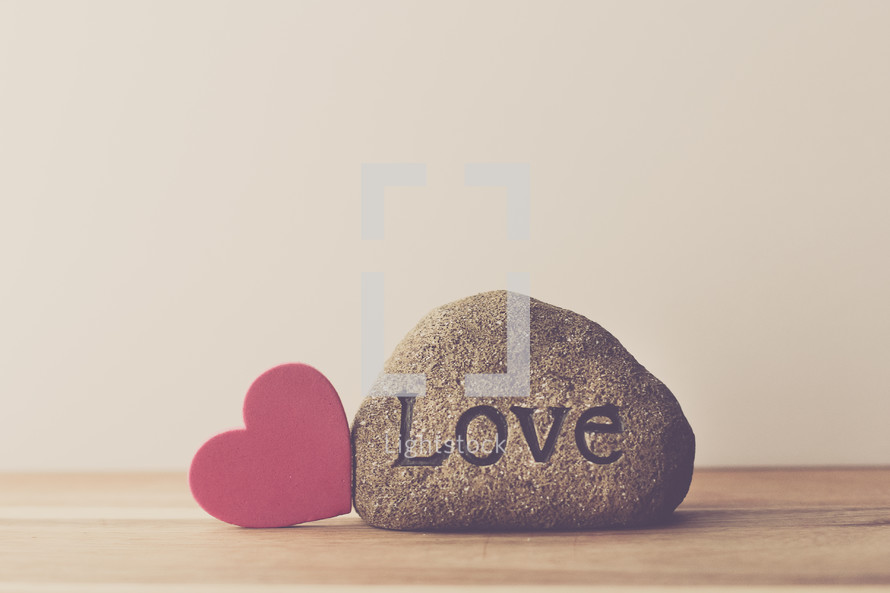 a rock with the word love and a red heart 
