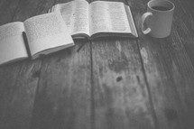 An open Bible and notebook next to a coffee mug