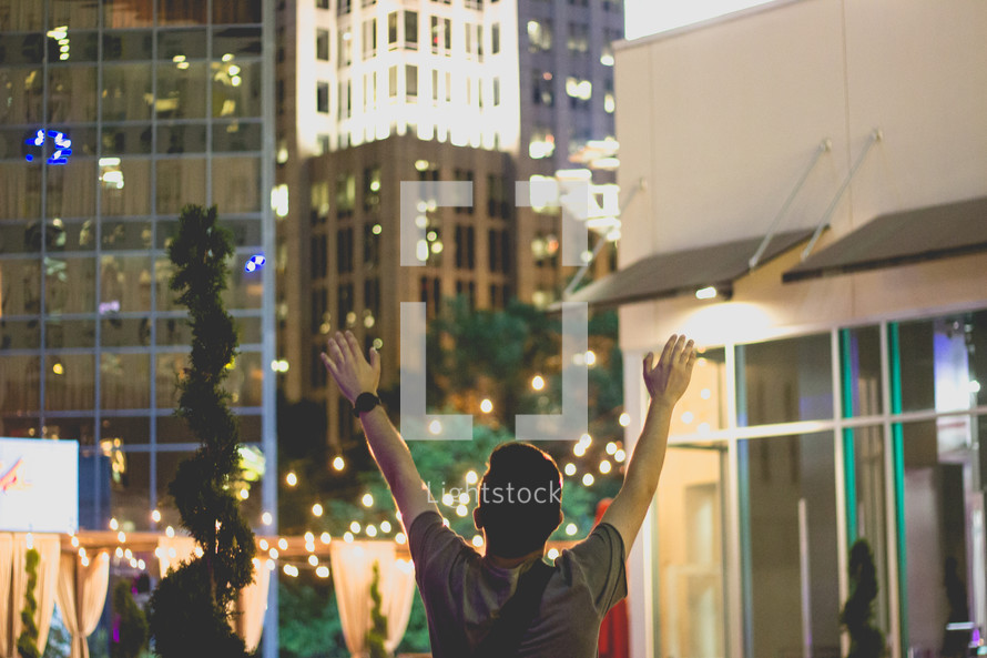 a man with raised hands in a city 