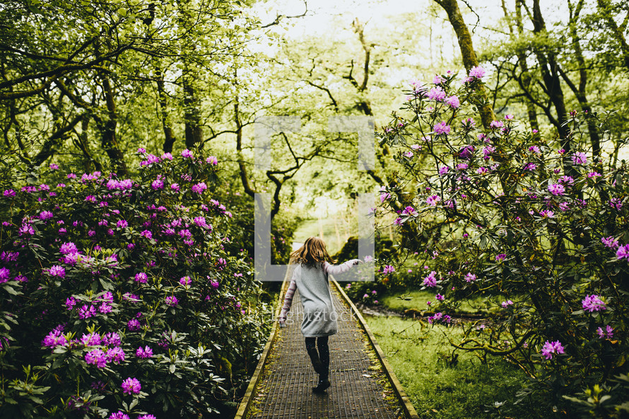 a girl walking on a path in the botanical gardens