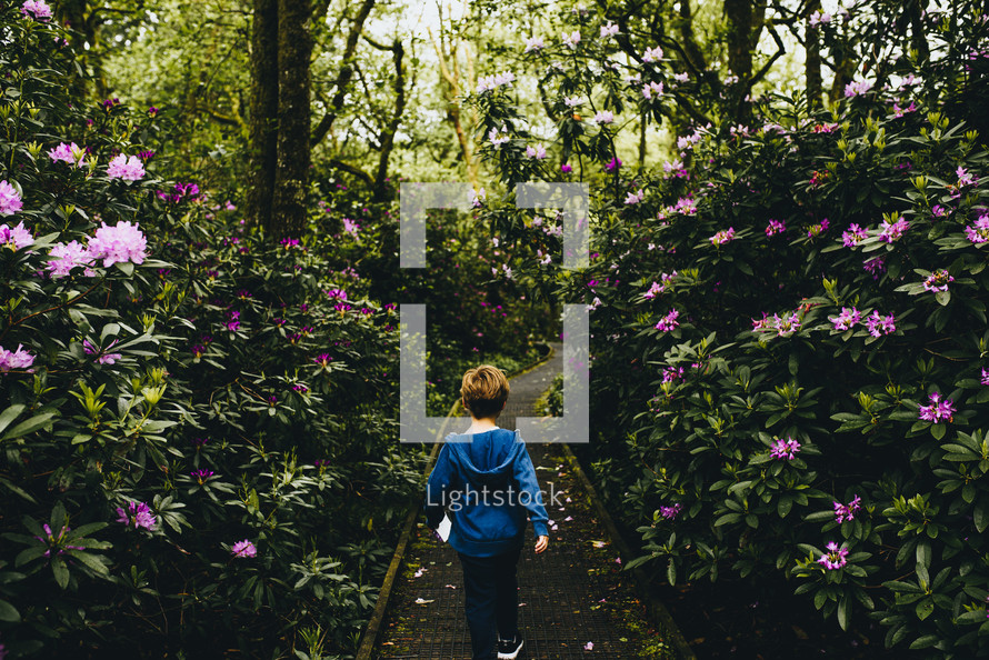 a boy walking through a botanical gardens 