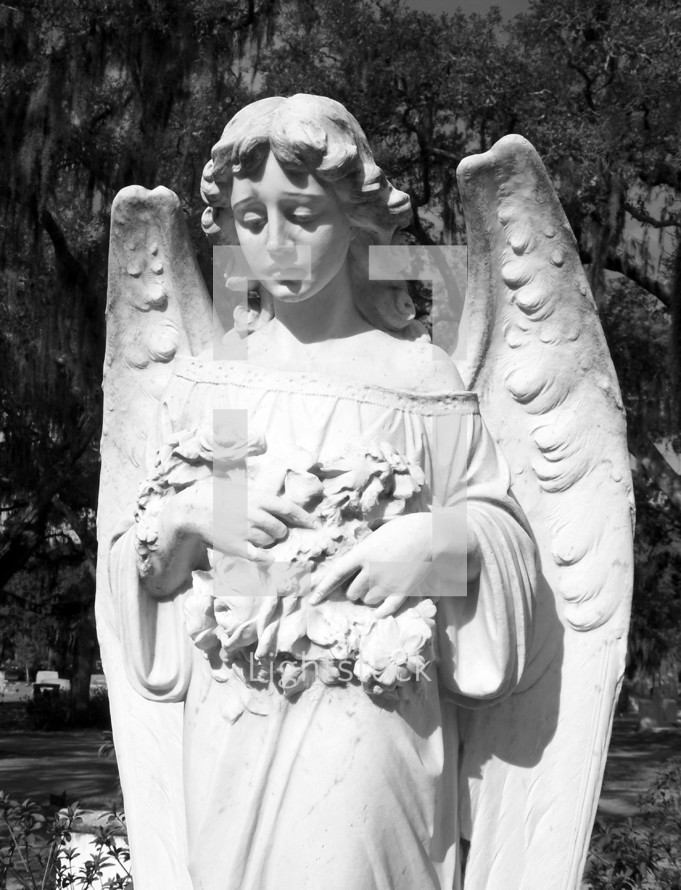 A tall and ornate statue of an angelic female figure stands in a historic cemetery in the southern United States of America where many historic figures are buried and serves as a historic landmark. 