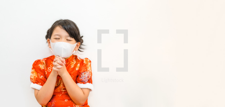 a praying child wearing a face mask 