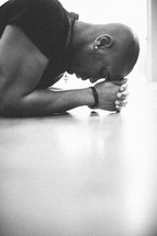 man kneeling in prayer with his hands and forehead on the ground