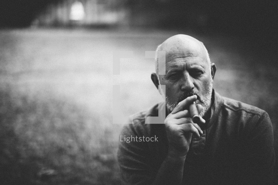 A bald man smoking a cigar