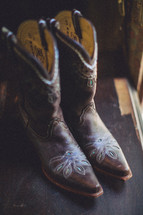 Cowboy boots resting on a wood floor. 