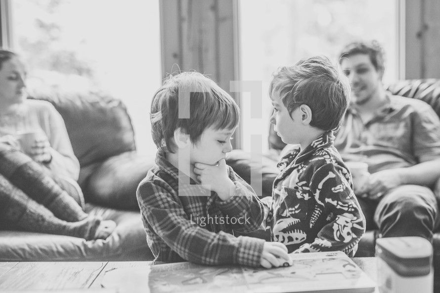 brothers in pajamas playing with cars on a coffee table 