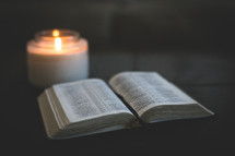 open Bible and candle on an ottoman 