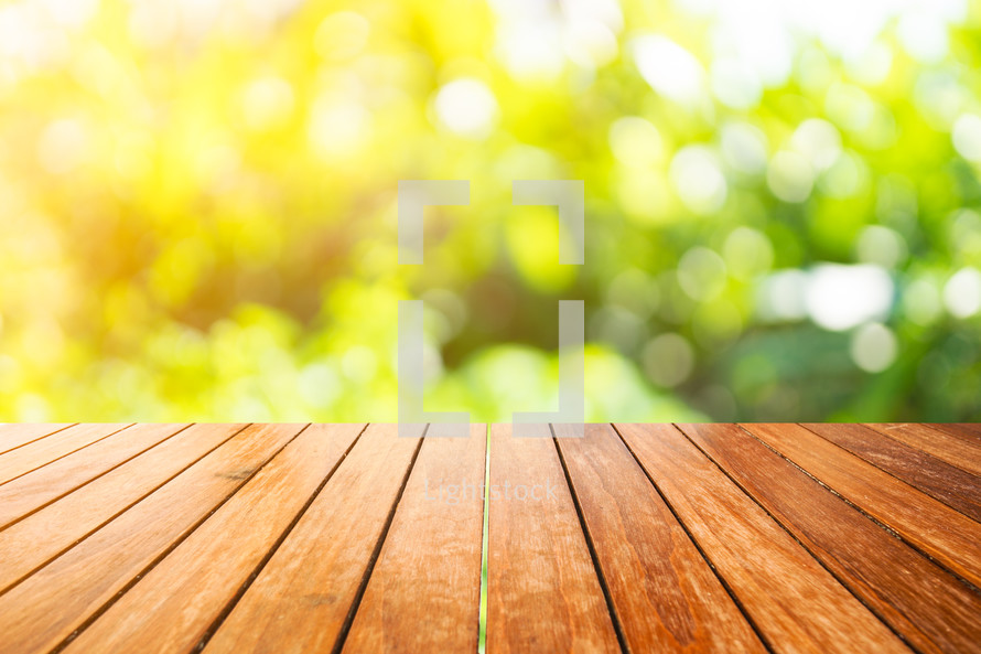 wood decking and bokeh sunlight on green leaves 