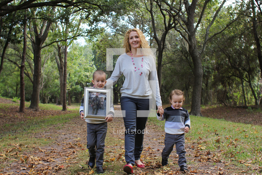 A mother and her children holding a framed picture of a soldier.