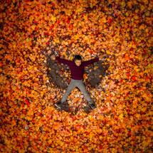 a boy playing in fall leaves 